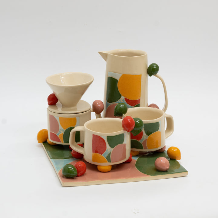 Ceramic tea set with colorful fruit design on a white background